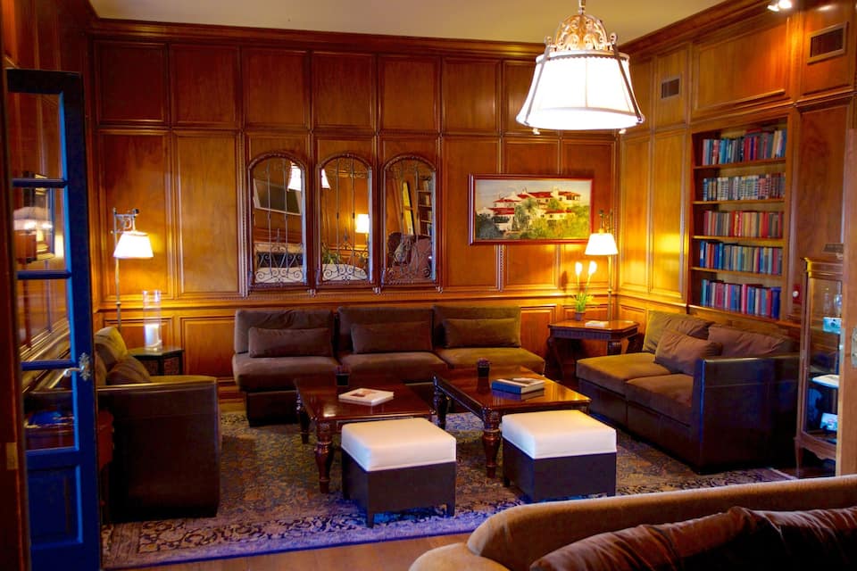 A cozy living room with wooden paneling, a chandelier, a bookshelf, and a painting on the wall.