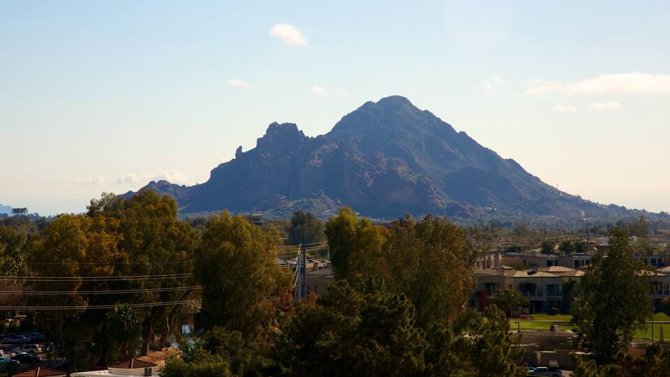 A mountain with a clear sky, surrounded by trees and buildings.