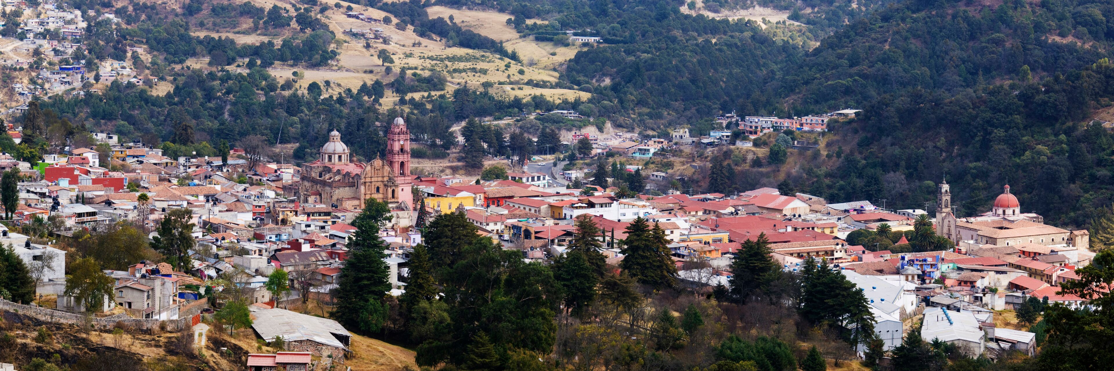 A town nestled in a valley with a prominent church and a hilltop church with a dome.