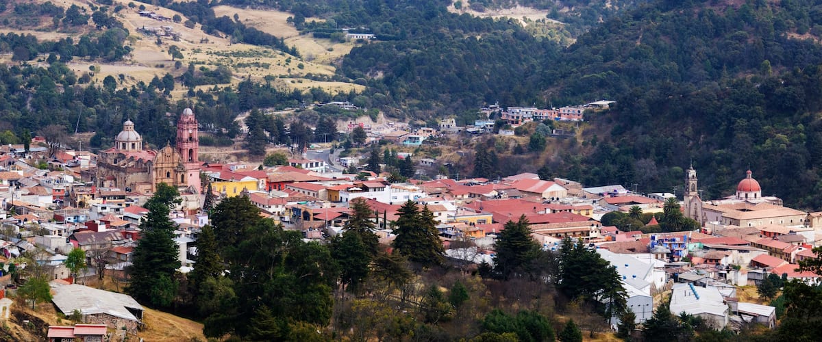 A town nestled in a valley with a prominent church and a hilltop church with a dome.