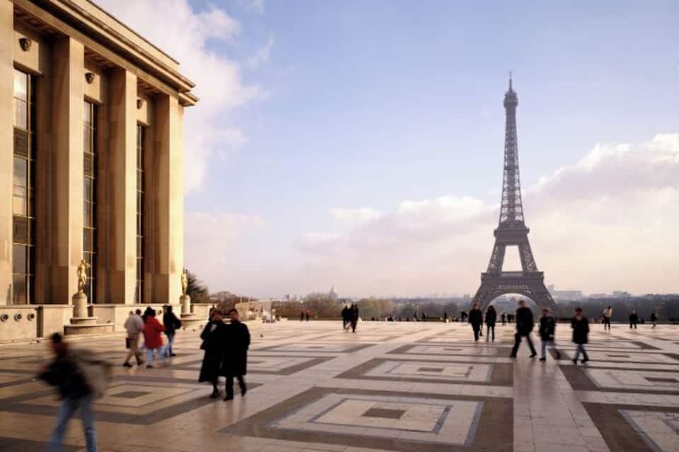 The Eiffel Tower in the background with people walking in the foreground.