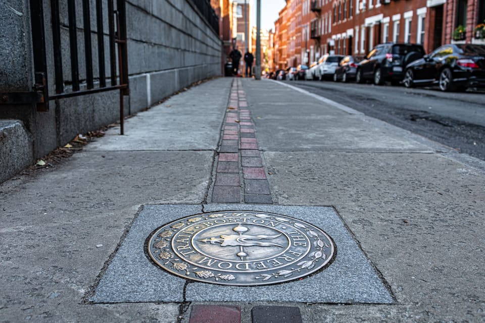 Een riooldeksel met de tekst 'BOSTON TRAIL' en 'FREEDOM' erin gegraveerd.