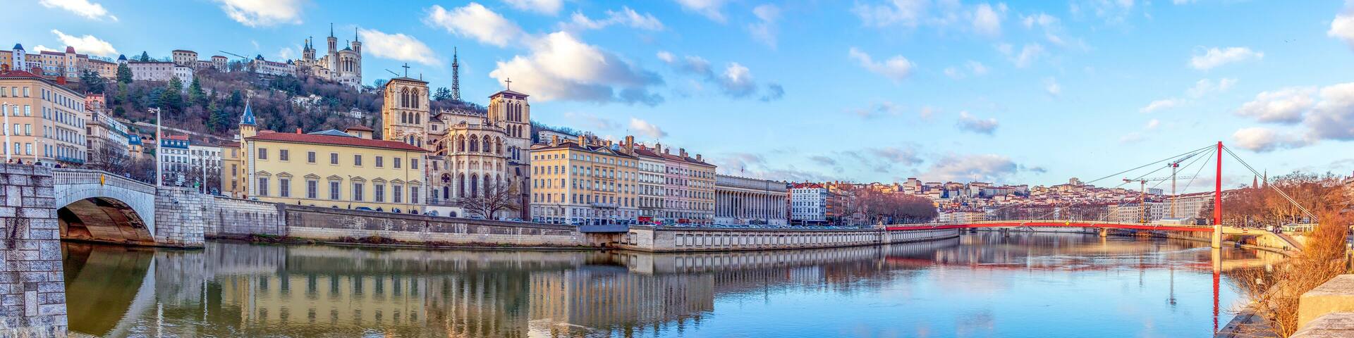 A river with a bridge, historic buildings, and a hill with a church.