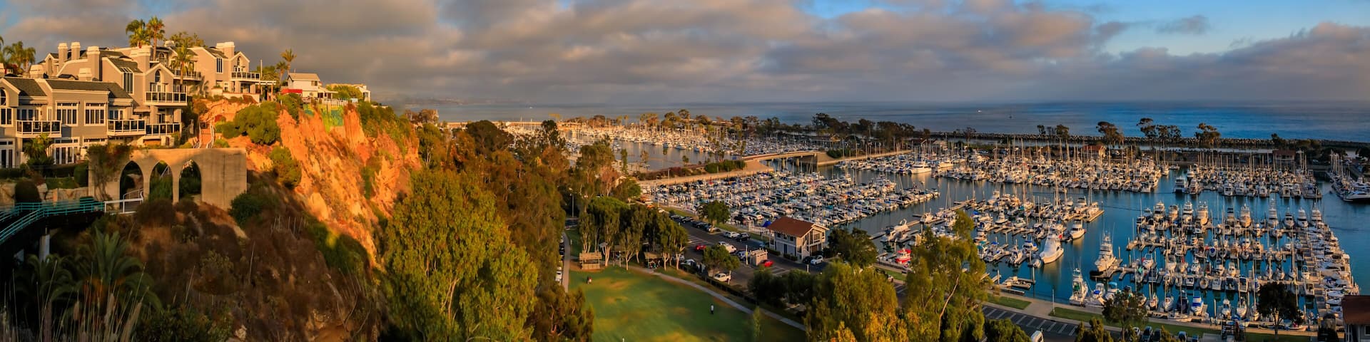 Sunset over luxury homes, yachts, and boats in Dana Point harbor, Orange County in Southern California on a cloudy day