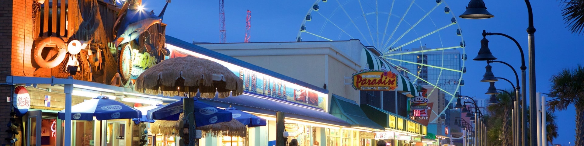 Un muelle con restaurantes, una noria y palmeras.