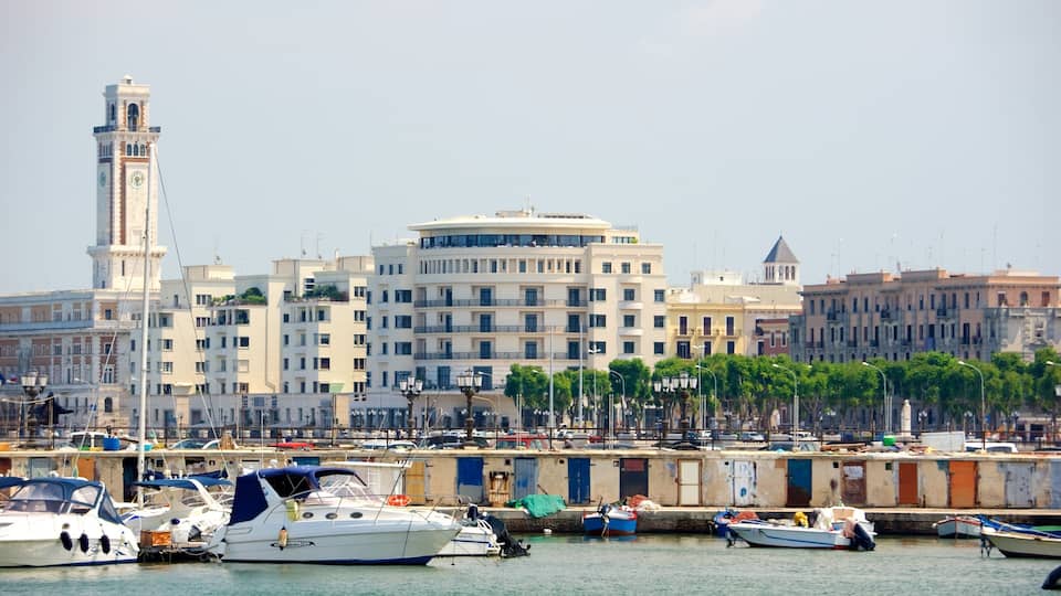 Un puerto deportivo con barcos amarrados, una imponente torre del reloj y edificios modernos al fondo.