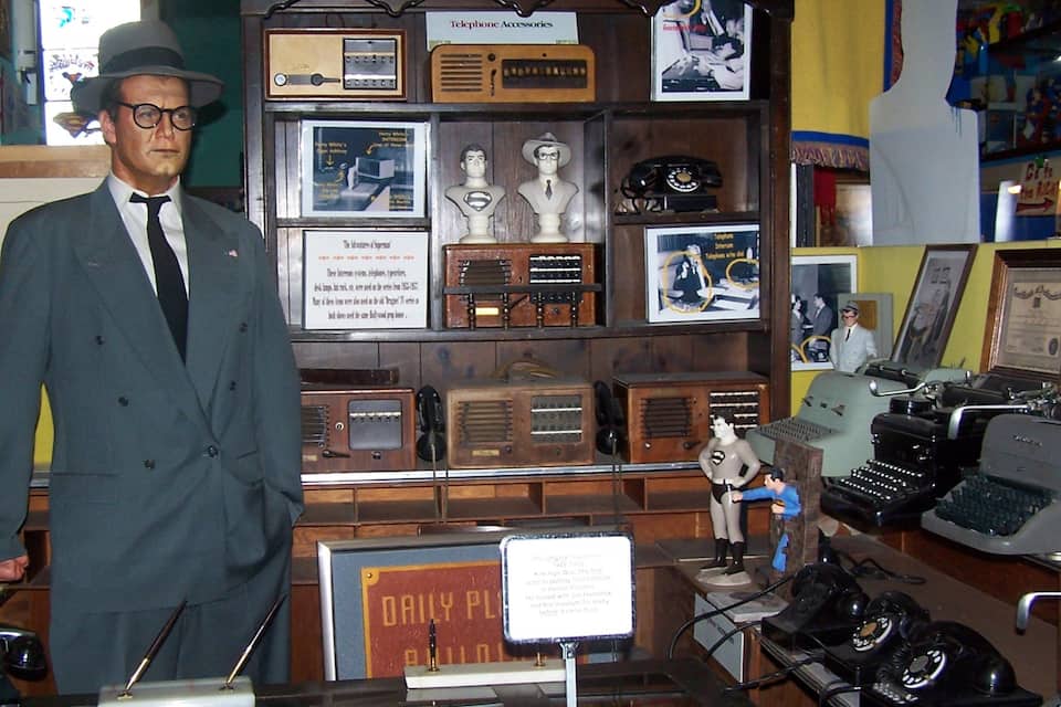 A display of vintage telephones and Superman figurines in a museum.