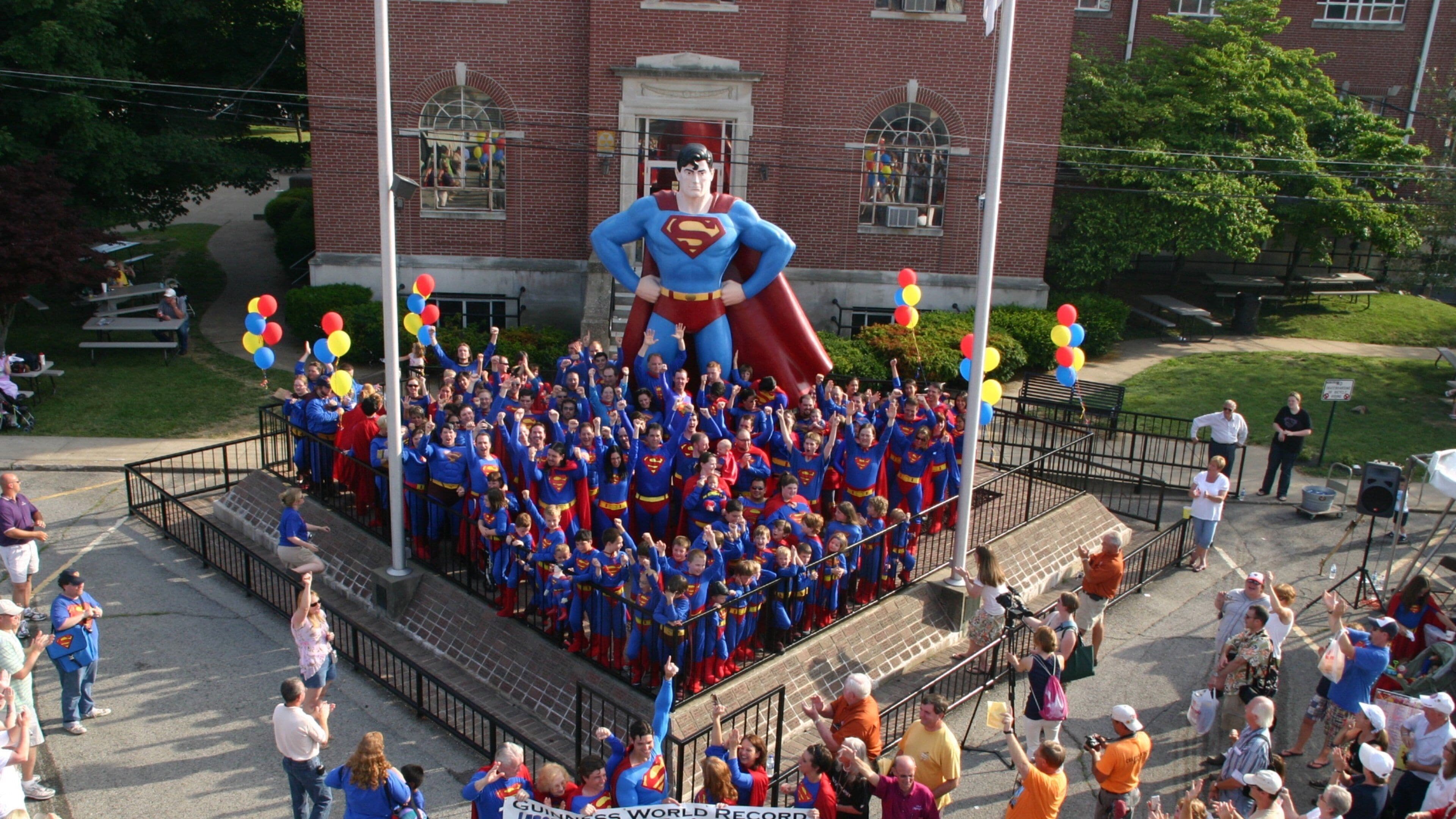 Superman Statue featuring a square or plaza and a statue or sculpture as well as a large group of people