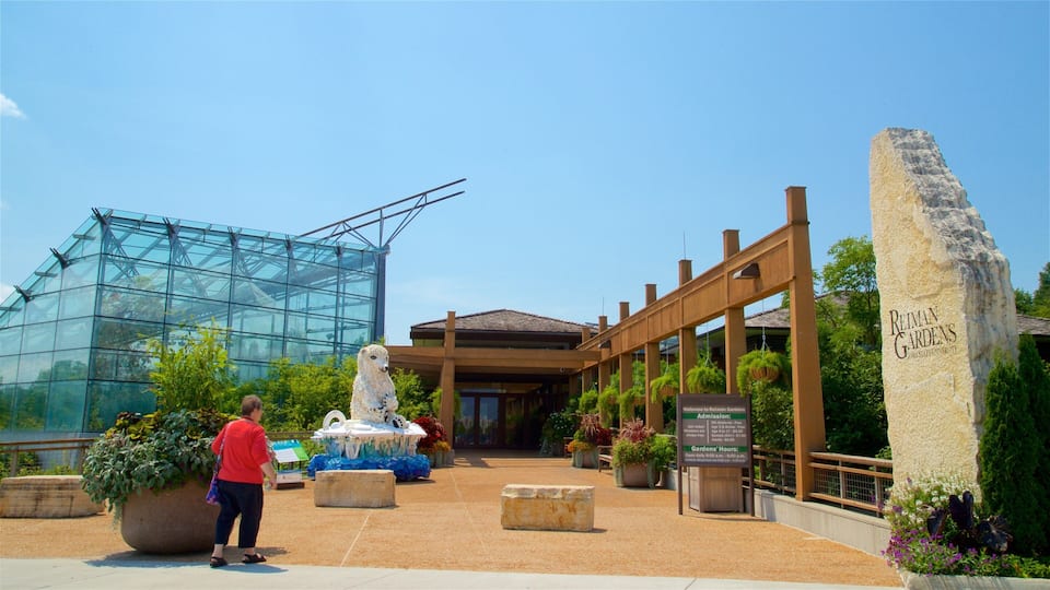 A glass greenhouse, a statue, and a stone sign at Reiman Gardens.
