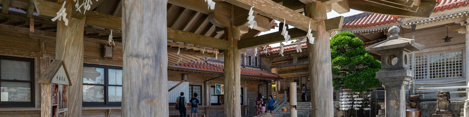 Una estructura de madera tradicional con techo de tejas, faroles de piedra y una fuente de piedra.