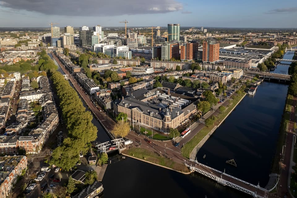 Vista aérea de una ciudad con un río, edificios modernos y un edificio histórico con una cúpula.