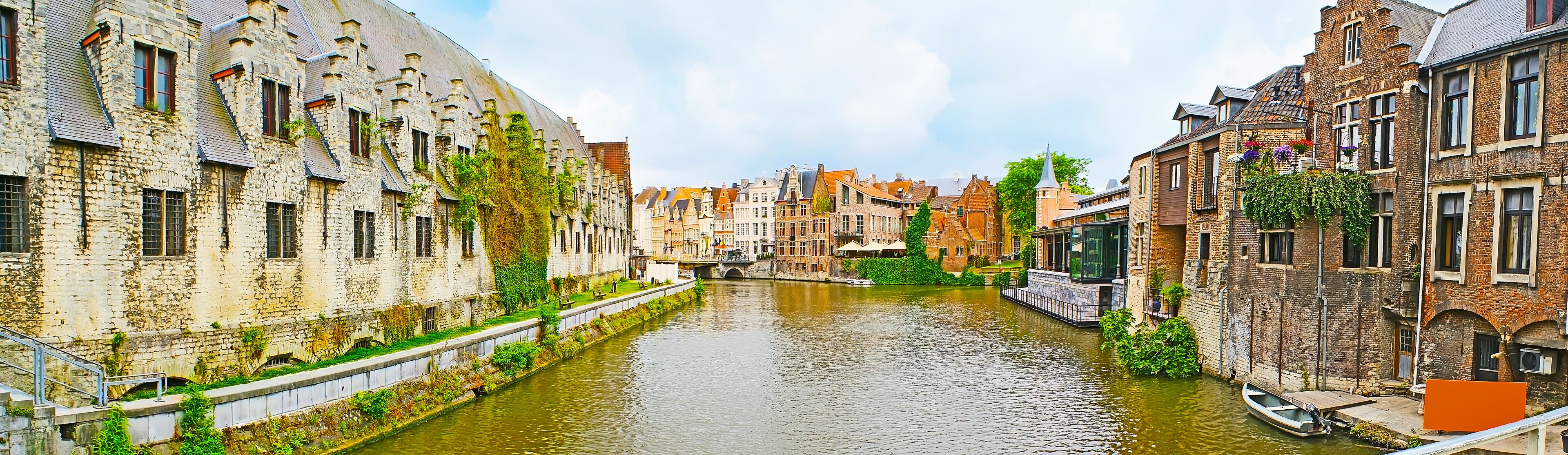 A narrow canal flanked by historic buildings with stone facades and steep roofs.