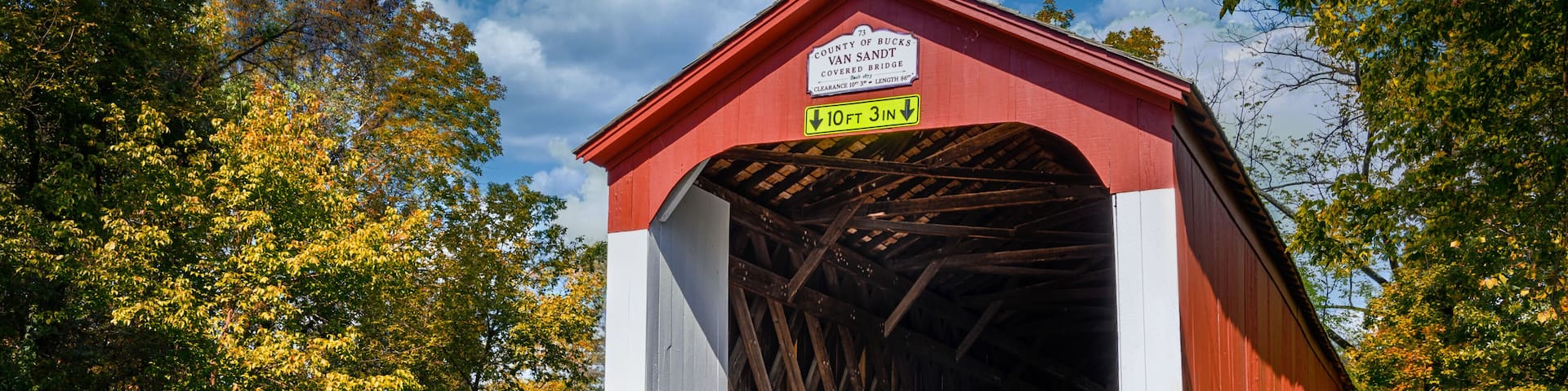 A red covered bridge with a sign indicating a clearance of 10 feet 3 inches.