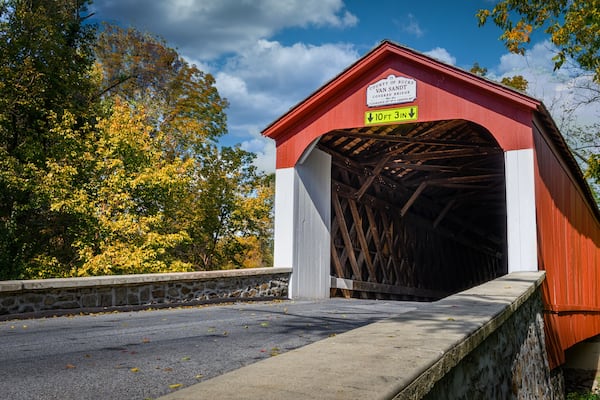 A red covered bridge with a sign indicating a clearance of 10 feet 3 inches.