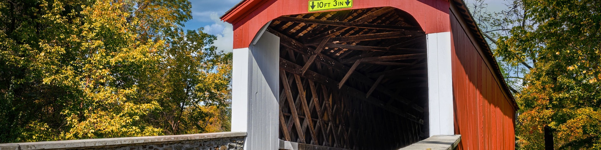 A red covered bridge with a sign indicating a clearance of 10 feet 3 inches.