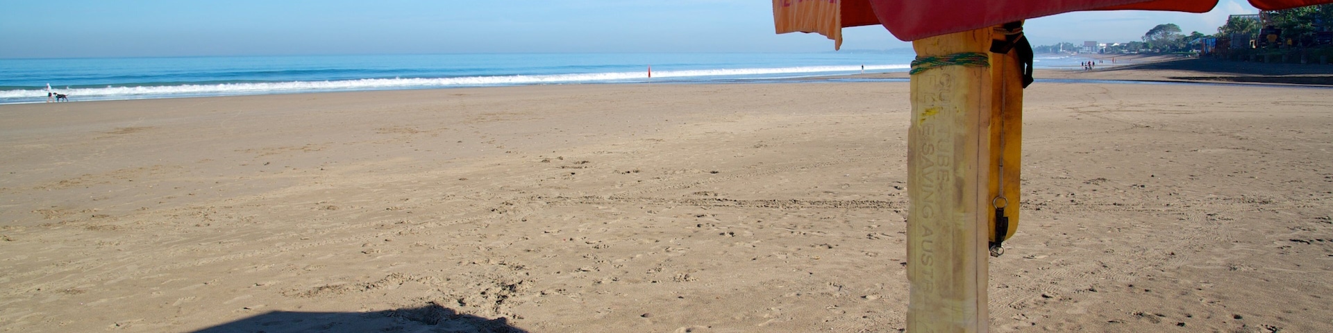 A lifeguard stand on a beach with a clear view of the ocean and distant shoreline.