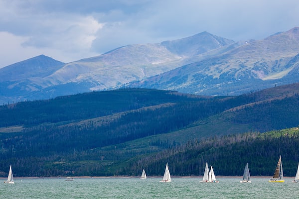Boats sailing on Lake Dillon in Colorado. Blue sky, blue choppy water with whitecaps on windblown water. Waves and sailboats with mountain backdrops.