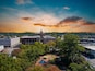 an aerial shot of a gorgeous autumn landscape at the Marietta Square with a water fountain surrounded by lush green trees and autumn colored trees with buildings at sunset in Marietta Georgia USA