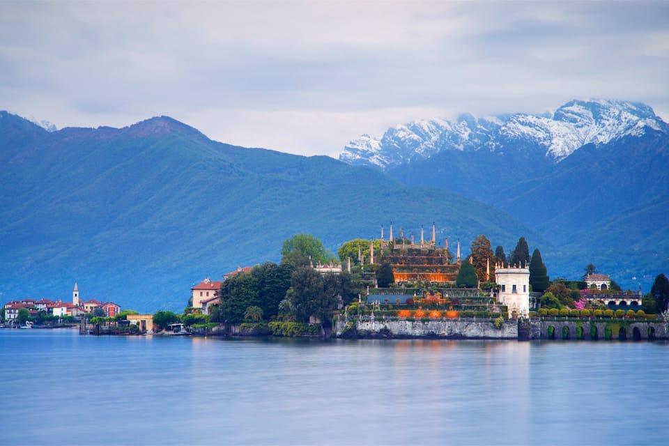 A historic island with a castle, surrounded by mountains and a calm lake.