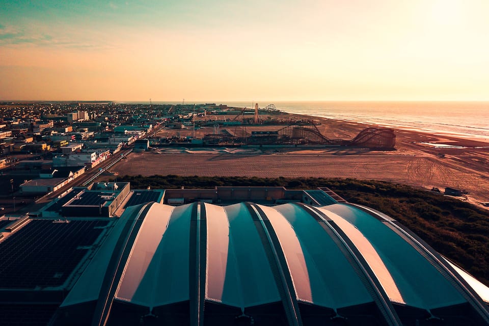 Eine Küstenstadt mit einer großen Solaranlage, einer Achterbahn und einem Strand.