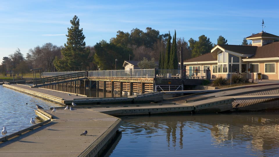 A waterfront with a dock, a house, and a bridge.