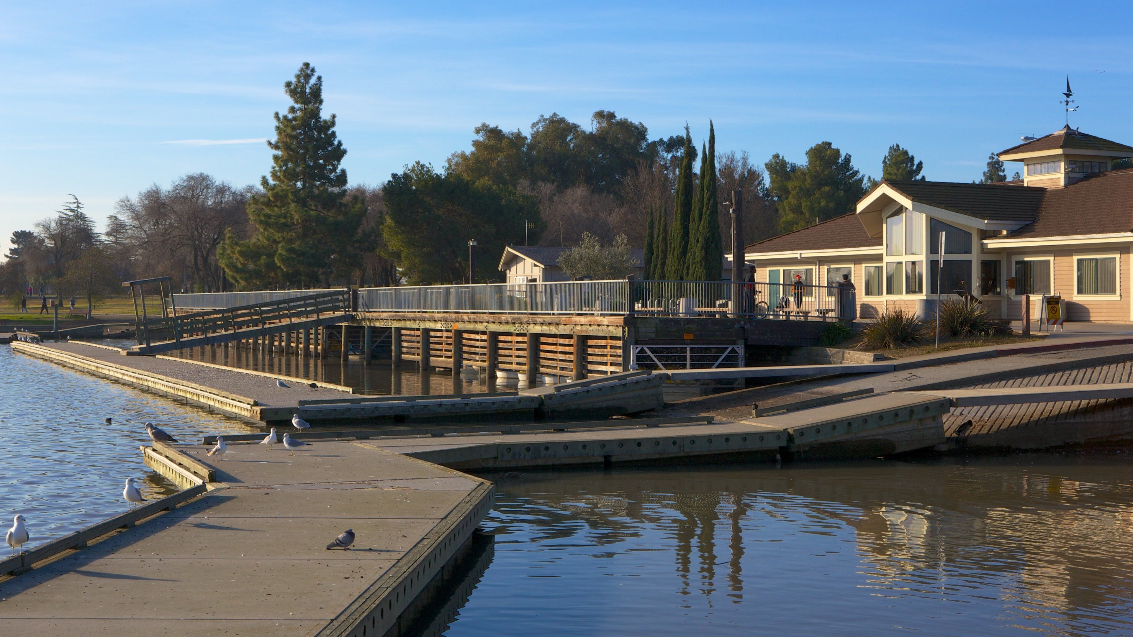 A waterfront with a dock, a house, and a bridge.