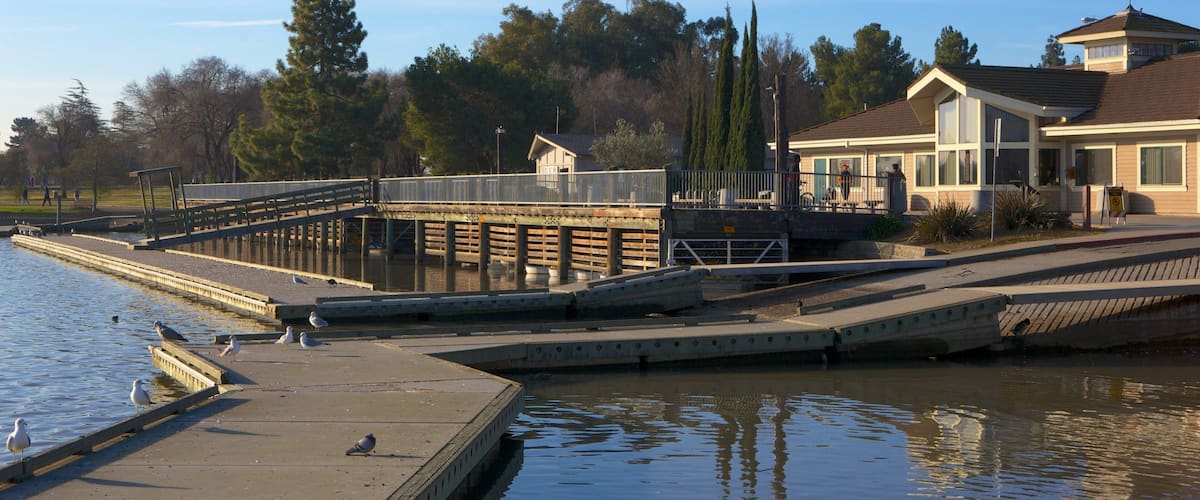 A waterfront with a dock, a house, and a bridge.