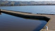 Un lac paisible avec une jetée en béton qui s’avance dans l’eau.