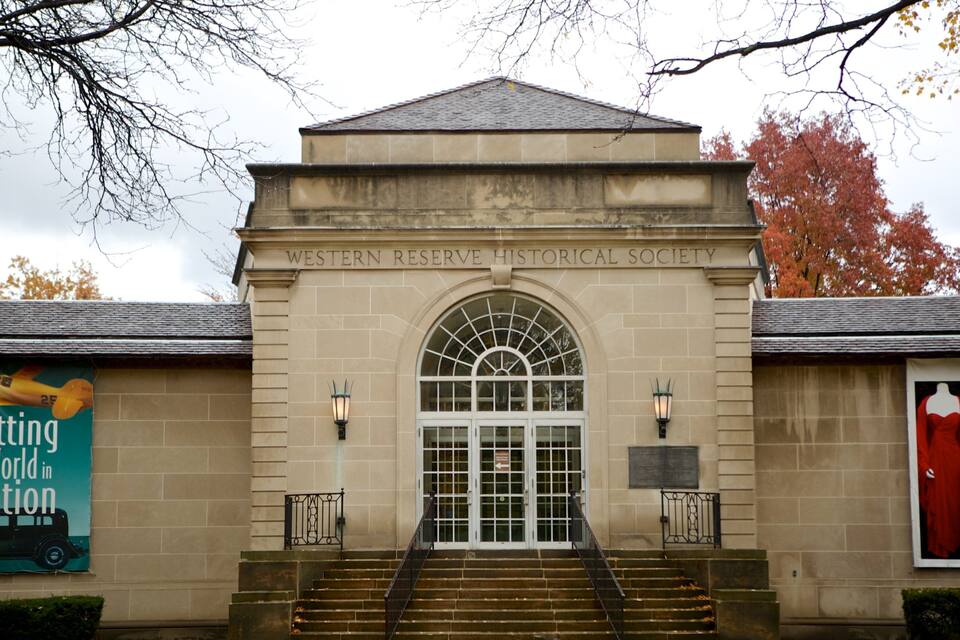 The entrance to the Western Reserve Historical Society building with a large arched doorway and steps leading up to it.
