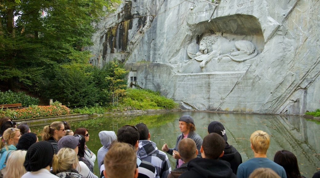 Lion Monument which includes a pond and a monument as well as a large group of people