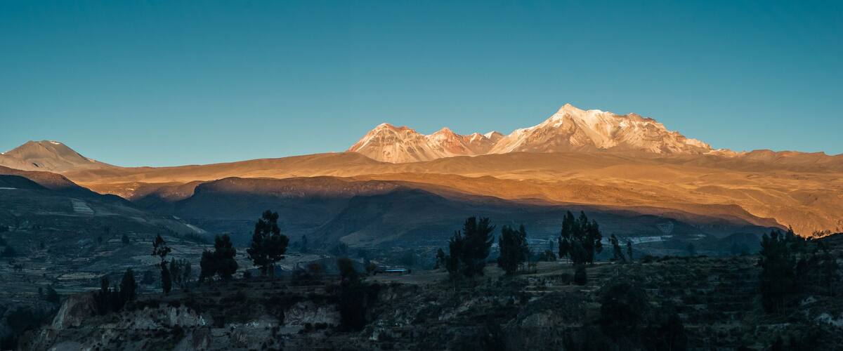 A mountain range with a prominent peak during sunrise or sunset.