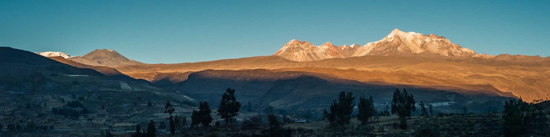 A mountain range with a prominent peak during sunrise or sunset.