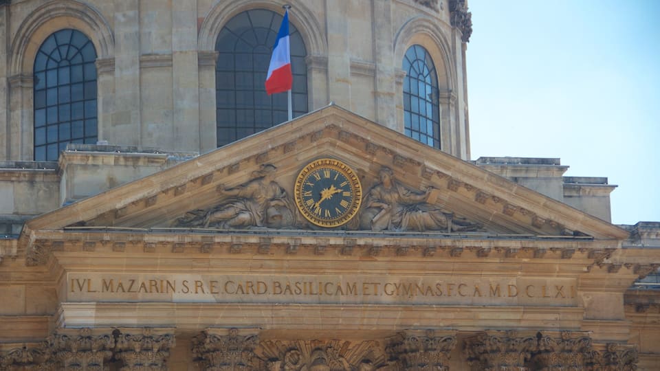 Fachada de edificio con un gran reloj, bandera francesa y adornos ornamentales.
