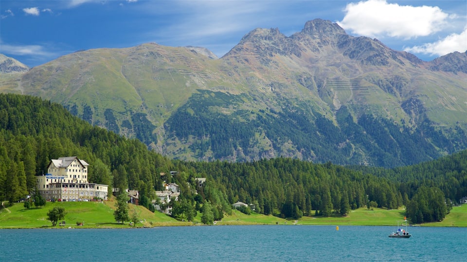 A mountain landscape with a large building on a lakeshore.
