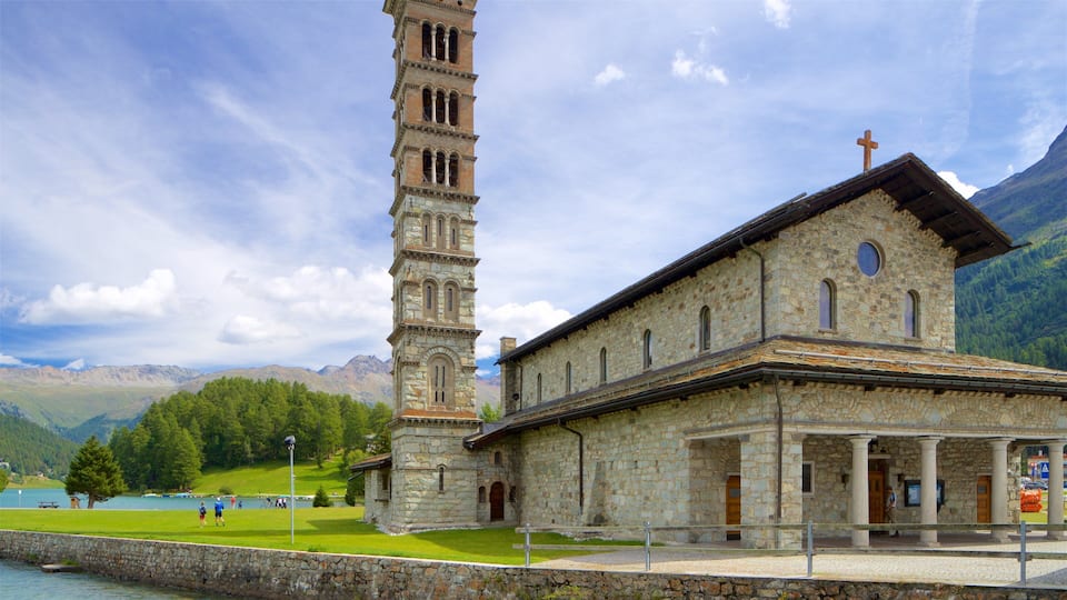 A stone church with a tall bell tower and a mountain backdrop.
