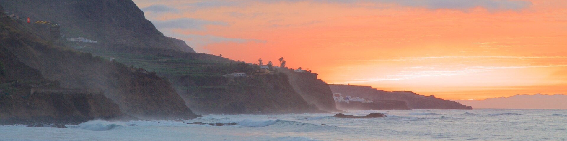 A coastal sunset with cliffs and waves.