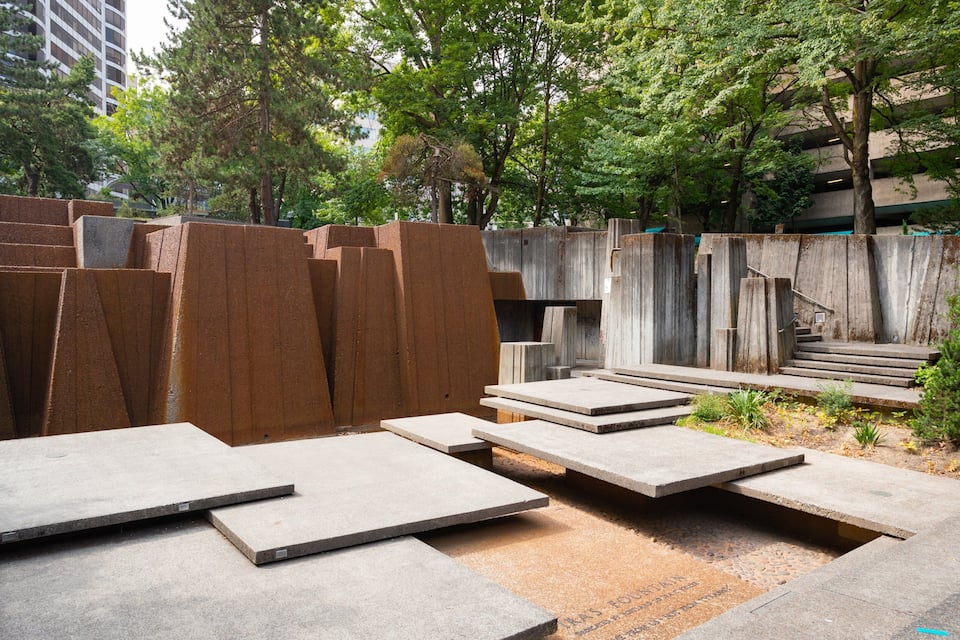 A park with stone benches and a wooden staircase.