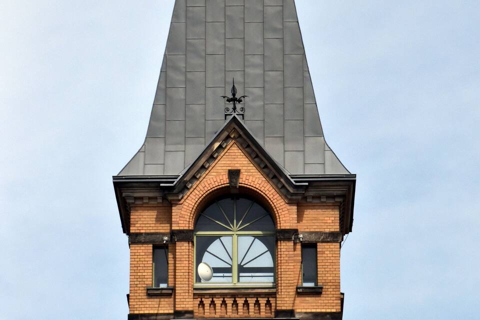 A brick tower with a pointed roof and a clock.
