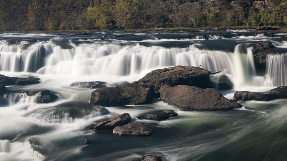 A waterfall cascading over rocks in a forested area.