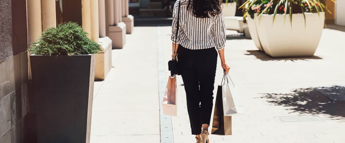 girl holding shopping bags on sunny day outdoors