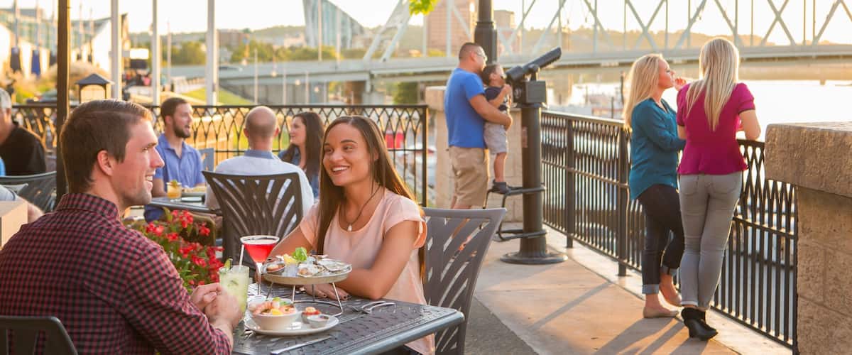 Newport on the Levee featuring outdoor eating as well as a small group of people