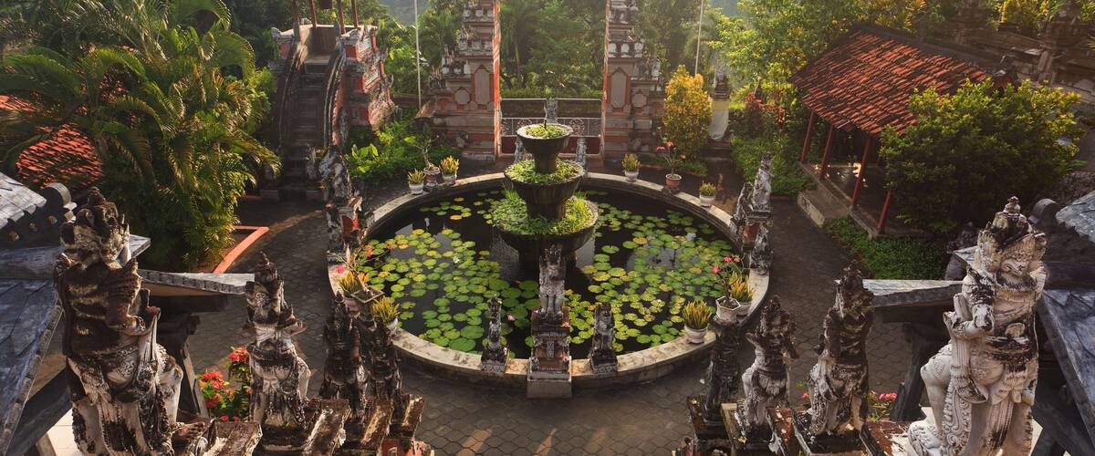 A temple complex with a central pond, statues, and a staircase leading up to the temple.
