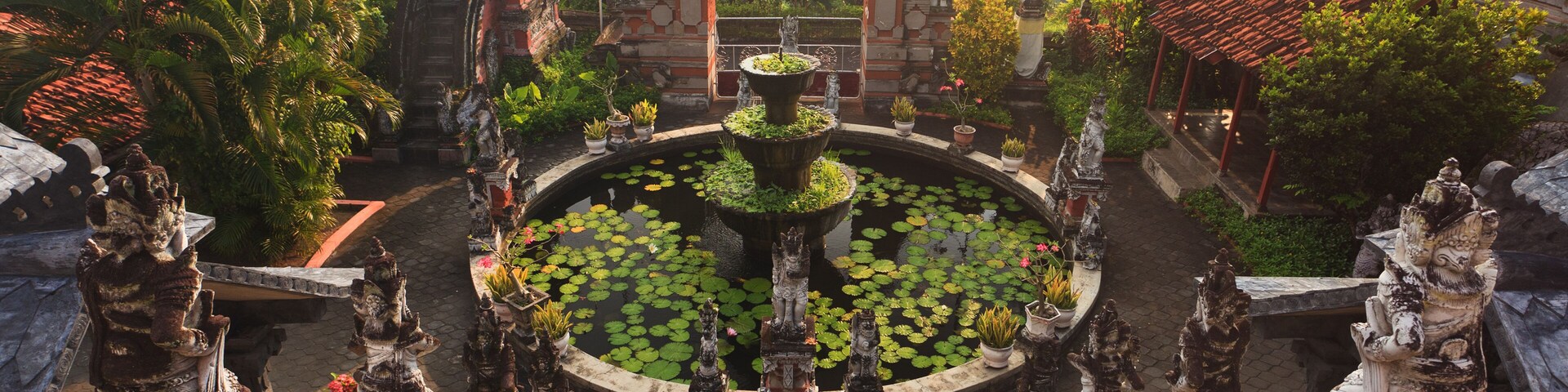 A temple complex with a central pond, statues, and a staircase leading up to the temple.