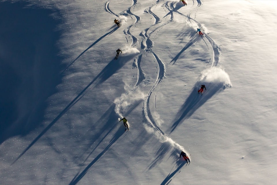 A group of skiers on a snowy slope with visible ski tracks.