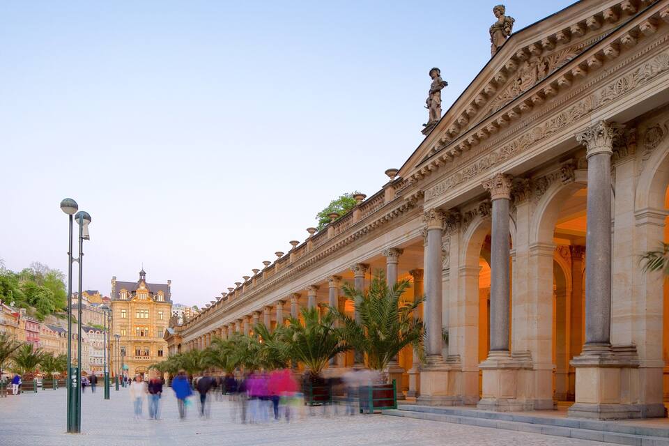 A grand building with ornate columns and statues, a cobblestone plaza, and palm trees.