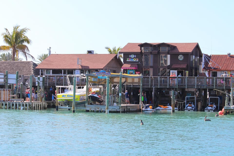 A waterfront area with docked boats, a pier, and buildings with commercial signs.