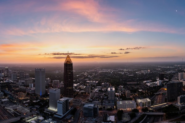 Une vue sur une ville au crépuscule, avec un gratte-ciel imposant et un coucher de soleil.
