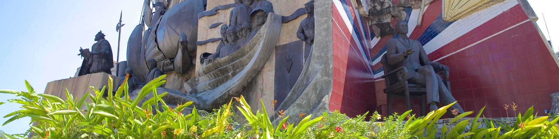 A large outdoor sculpture with a cross, a ship, and a building with multiple crosses.