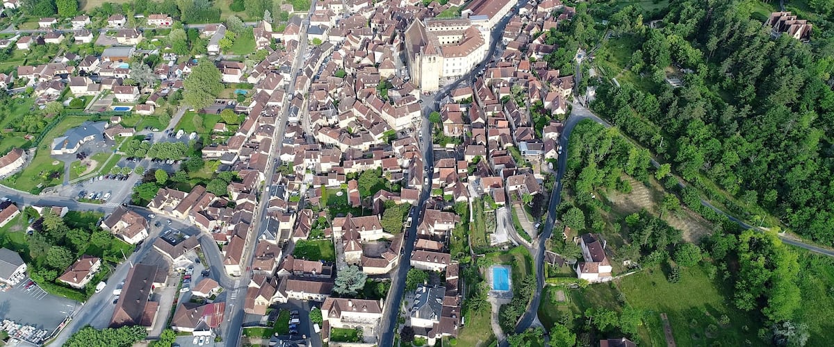 An aerial view of a densely packed residential area with a prominent church and surrounding greenery.