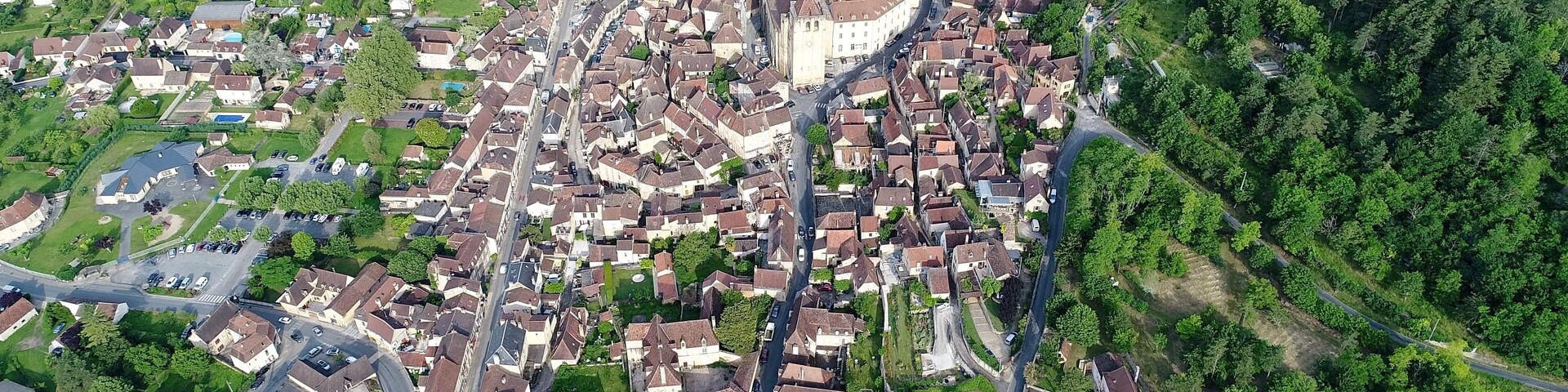 An aerial view of a densely packed residential area with a prominent church and surrounding greenery.